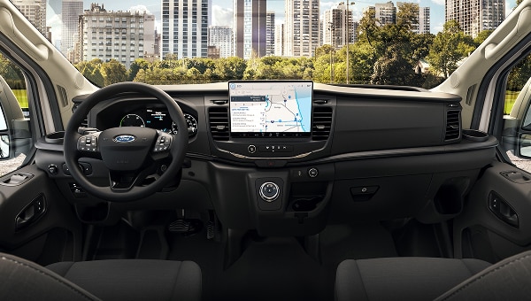 Interior de Ford E-Transit con pantalla de  navegación central, volante y vista de ciudad.